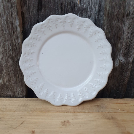 Enfärgar keramikassiett med en bård av granar