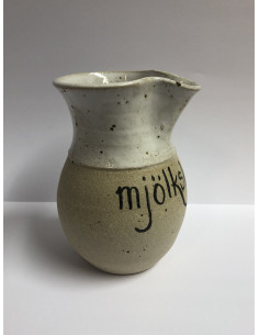 En drejad liten kanna med texten Mjölkskvätten och ett målat ledkryss 2