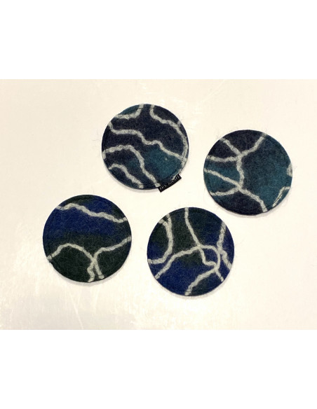 Runda glasunderlägg av tovad ull i färgerna, blått, grönt, vitt