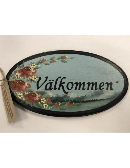 Träskylt som säger Välkommen, målad i allmogefärger och med fjäll och blommor som motiv