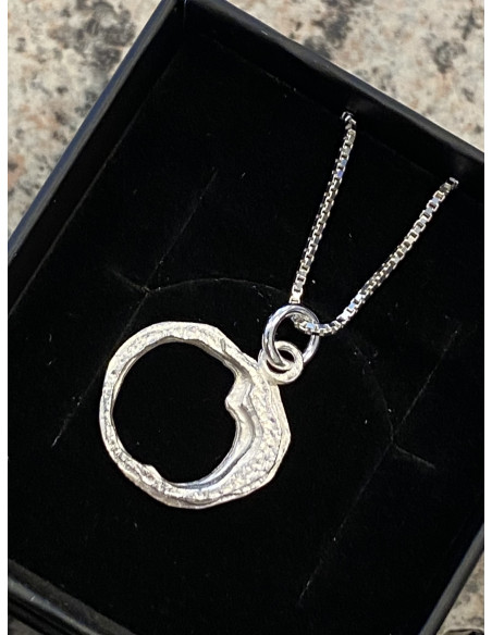 Halsband i silver med en berlock som visar en hålighet som återfinns i Döda Fallet i Ragunda Kommun