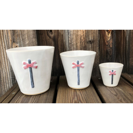 Keramikmugg i tre storlekar i vit glasyr med ett rött ledkryss på